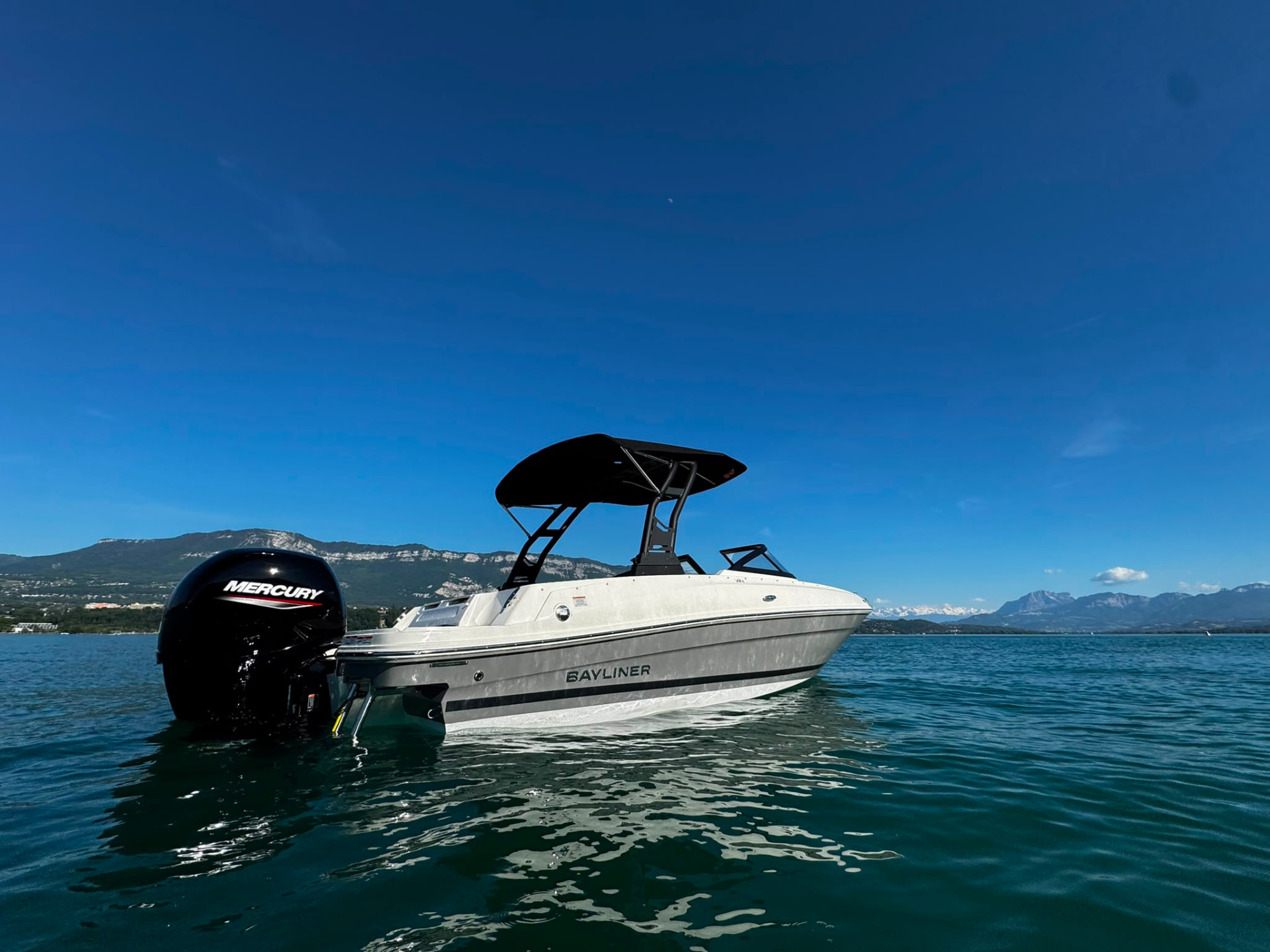 Le Bayliner VR4 seul sur les eaux calmes du Lac du Bourget, sous un vaste ciel matinal