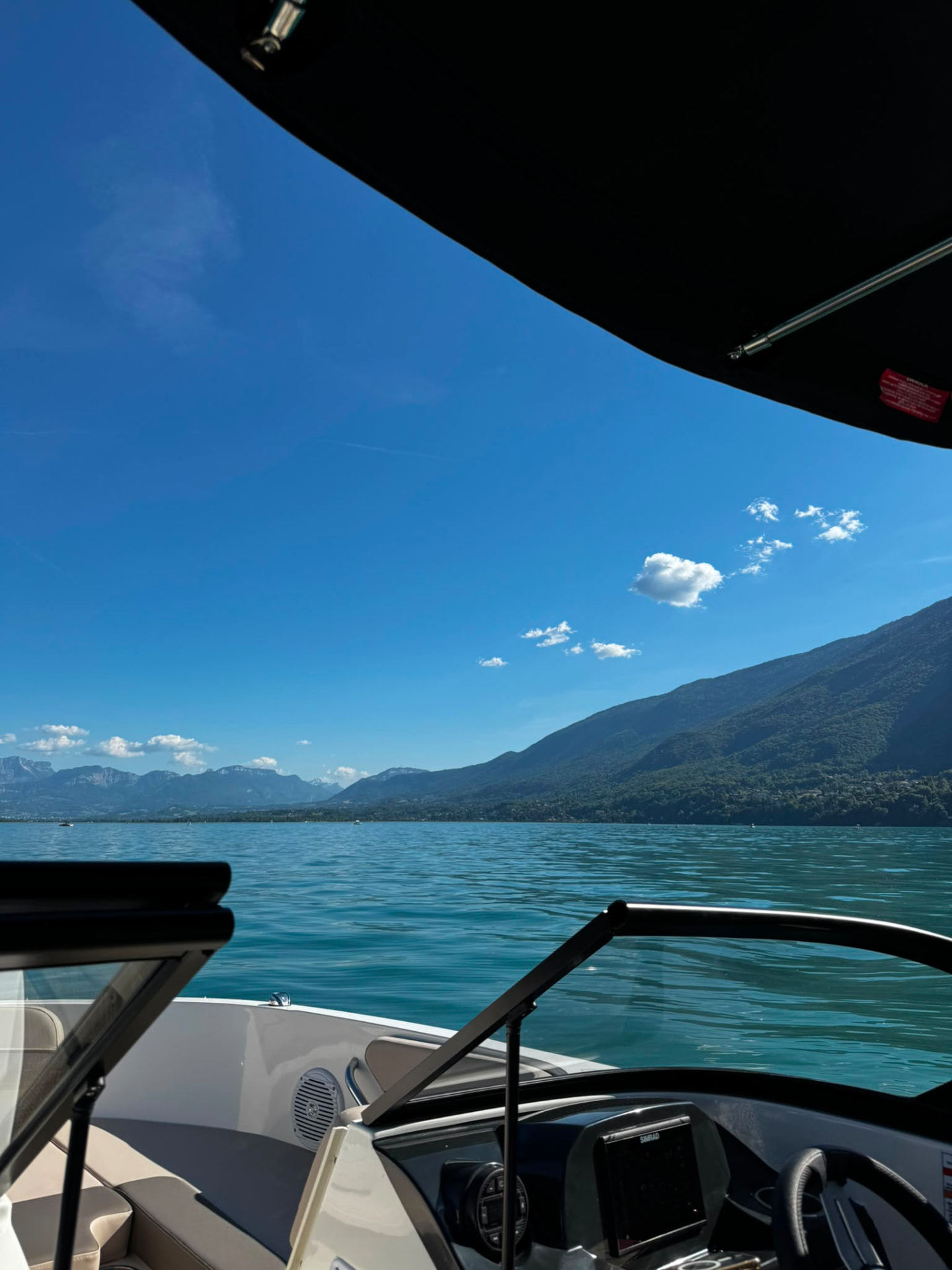 La vue sur le lac et les montagnes depuis le poste de pilotage du bateau, pare-brise et eau à l'horizon